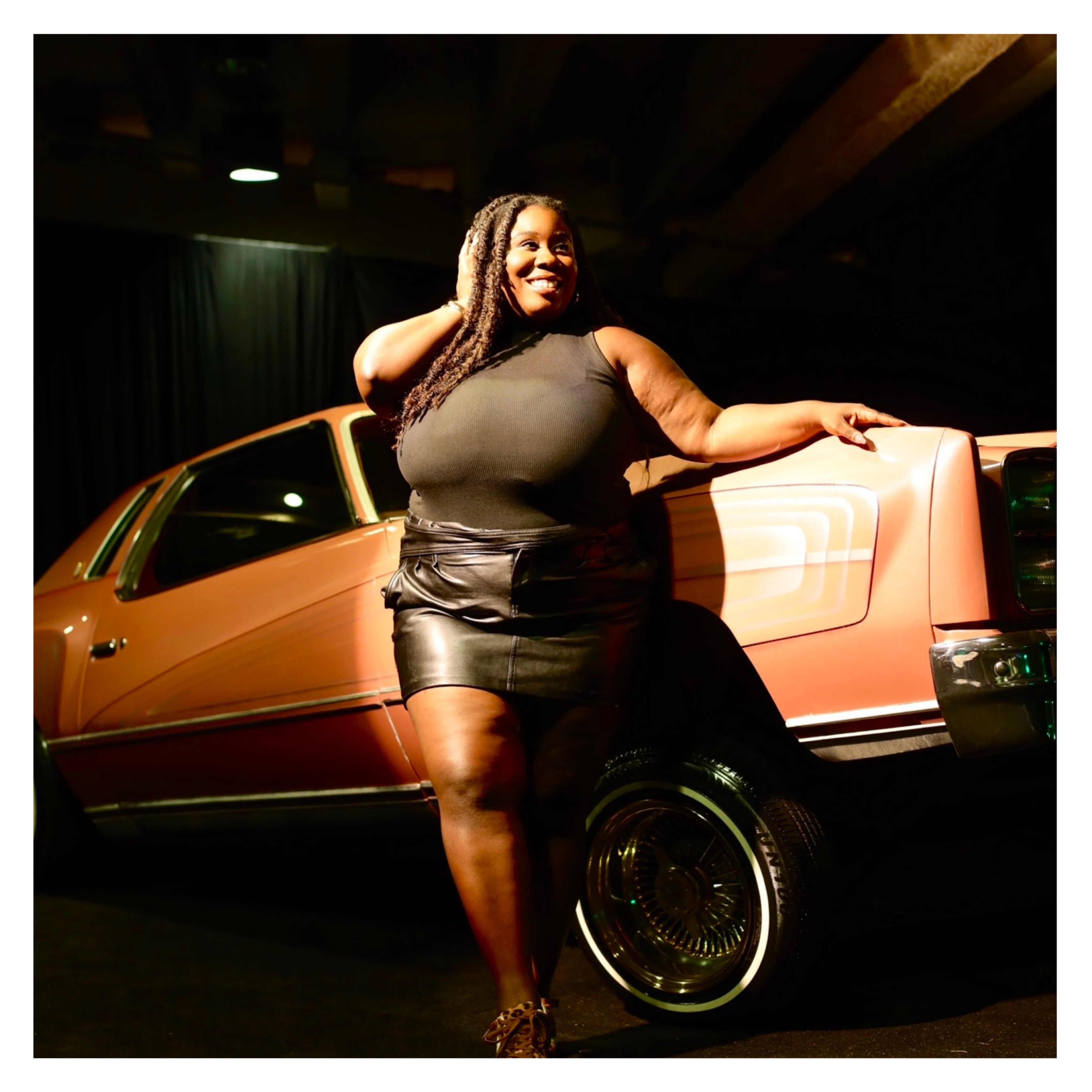 Portrait against a vintage lowrider, laughing